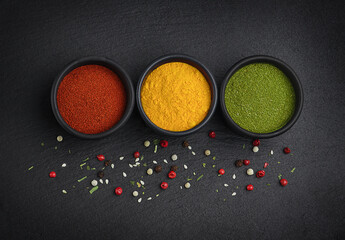 Herbs and spices for cooking on black stone plate. Paprika, turmeric and dried bay leaf. Look like traffic lights .