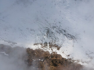 aerial drone shot in natural mountains landscape with snow in winter. cloudy day with fog. italian alps. trekking trail with people hiking, alternative safe sport during covid pandemic