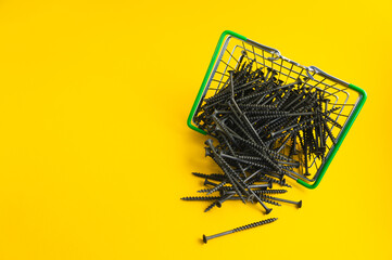 Screws in a shopping basket on a yellow background