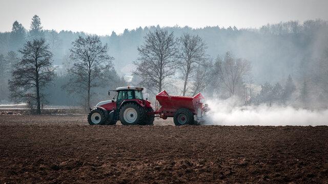 Landwirt kalkt mit dem Traktor den Acker im Fr&uuml;hjahr - Bodenkalk