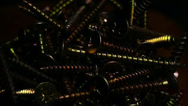 Strobo of a bunch of bolt screws in a glass on a wooden surface