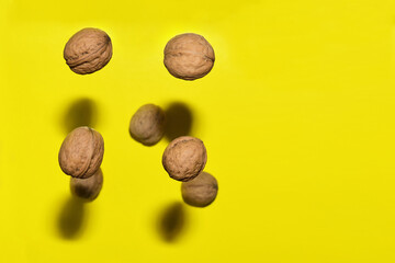 walnuts suspended in levitation on different planes against a yellow background