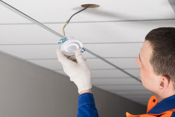 a worker installs lighting equipment into the false ceiling