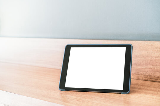 The mockup tablet stands on the wooden desk in the corner of the office background with natural light