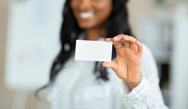 Cropped view of businesswoman demonstrating empty business card with mockup for design at office, selective focus