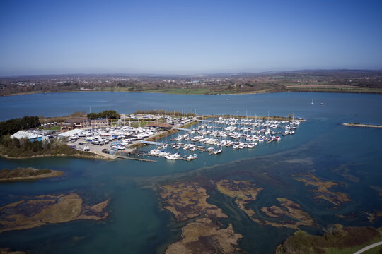 Northney Marina with moored yachts and boats on the pontoons situated on shore of Hayling Island in the beautiful Langstone Harbour., aerial view.