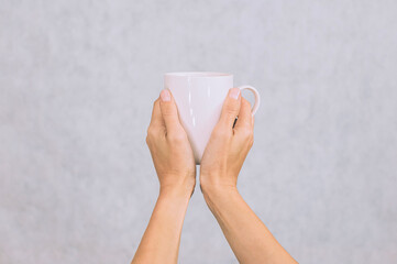 White mug for coffee, tea in the hands of a girl. On a white background.