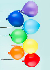 Small inflatable balls of rainbow colors hang on a ribbon. Holiday content