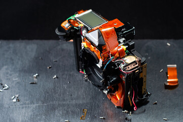 Professional repair of photographic equipment. Disassembled SLR camera on stone table on dark...