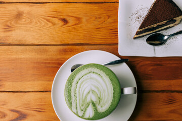 Cup of matcha coffee in a large white mug with cake on a wooden brown table