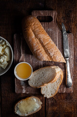 Fresh cut baguette on a wooden background with honey and butter