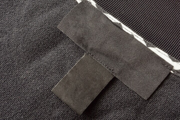Blank black laundry care clothes label on black fabric texture background