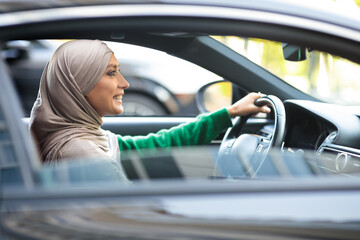 Cheerful muslim woman driving her new car