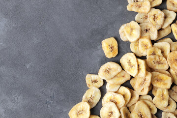 sweet banana slices on grey background, top view with space for text. Dried fruit as healthy snack