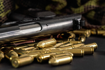 Yellow brass and brown bronze bullets, with black gun near, closeup detail