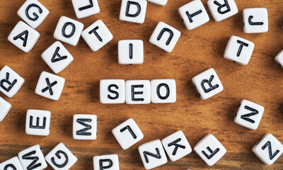 Small white and black bead cubes on wooden board, letters in middle spell SEO - Search Engine Optimization concept
