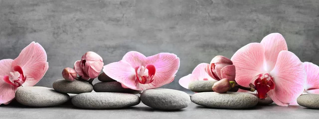 Selbstklebende Fototapeten Badekurortsteine und rosafarbene Orchidee auf dem grauen Hintergrund. © Belight