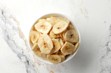 plate with banana slices on marble table, top view. Dried fruit as healthy snack