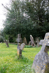 View of an old graves with green grass in the garden around St Andrew's Church in Castle Combe.