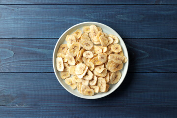 Heap of sweet banana slices on  a plate on a blue wooden  background. Dried fruit as healthy snack