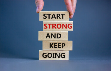 Start strong and keep going symbol. Concept words 'Start strong and keep going' on wooden blocks on a beautiful grey background. Businessman hand. Business, motivational and start strong concept. - obrazy, fototapety, plakaty