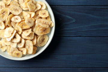 Heap of sweet banana slices on  a plate on a blue wooden  background. Dried fruit as healthy snack