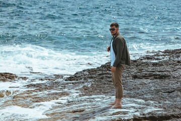 Fototapeta na wymiar man walking by rocky beach in windy day summer vacation. enjoy sea view