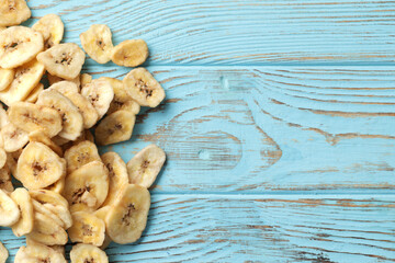 Heap of sweet banana slices on a blue wooden  background. Dried fruit as healthy snack