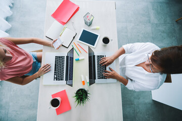Crop businesswomen browsing laptop and smartphone for work at workplace