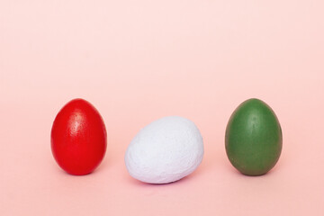 Red, white, green decorative eggs on a pink background. Easter background, Colored easter eggs on a light background.