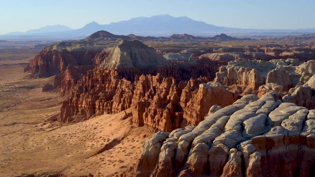 Wide aerial, white tipped mountains in Goblin Valley at sunset