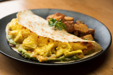 Huevos Rancheros.  Three scrambled eggs in a flour tortilla with refried beans, guacamole and shredded cheese.