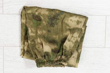 Closeup Camouflage pants on wooden background, green khaki pants. Unfolded camouflage soldier elastic pants on wooden background.