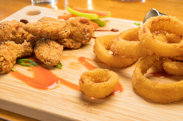Chicken wings and onion rings with a pitcher of beer.