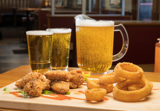 Chicken wings and onion rings with a pitcher of beer.