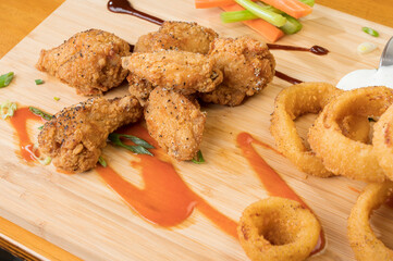 Chicken wings and onion rings with a pitcher of beer.