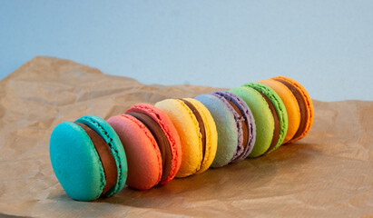 Multicolored macarons with wrapping craft paper on a gray background.