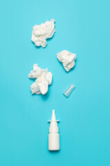 Obraz premium Nasal spray and crumpled wipes on a blue background.