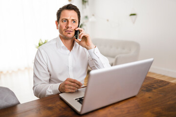 surprised business man working on laptop online sitting at kitchen table