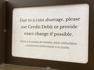 Bilingual sign in English and Spanish language: Due to a coin shortage, please use credit or debit card or provide the exact change.