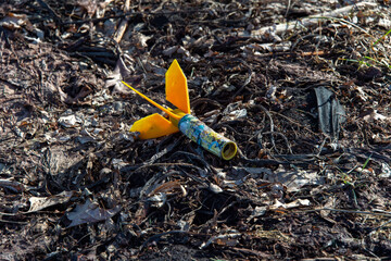 An expended plastic fireworks rocket lays on the ground.