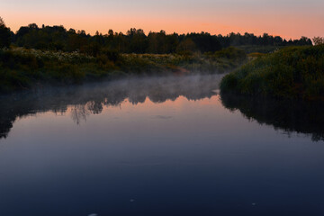 Naklejka na ściany i meble Fog over the river. Summer evening.