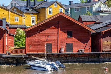 Fototapeta na wymiar Old red wooden building and modern boat in Porvoo, Finland