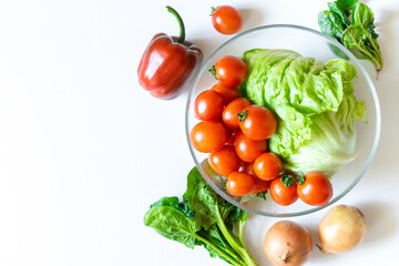 Bowl of organic and bio fresh vegetables tomato, pepper on white table background with copy space. Healthy natural ripe vegetarian vegetables concept. Ingredients for salad