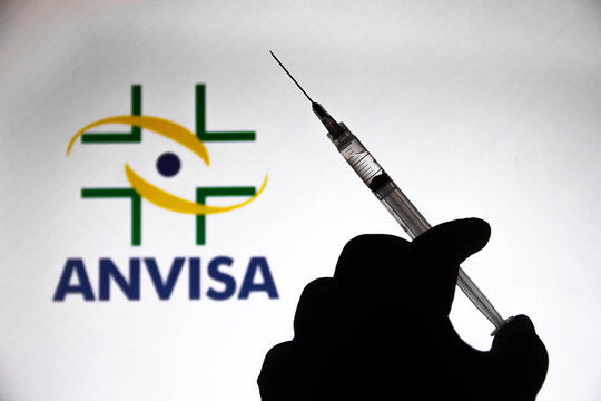 March 30, 2021, Brazil. In this photo illustration the medical syringe is seen with National Health Surveillance Agency (Anvisa) company logo displayed on a screen in the background.
