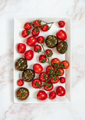 Naklejka na ściany i meble Various kind of ripe tomatoes on white plate with with white marble background.