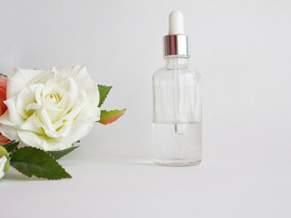 Cosmetic bottle with pipette isolated on white background. glass bottle with moisturizing serum with flowers, place for text. Beauty cosmetic skin care concept.