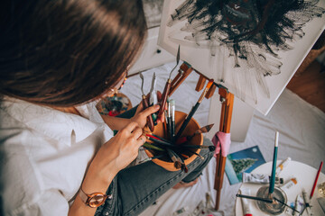 Beautiful talented female artist painting at her home.