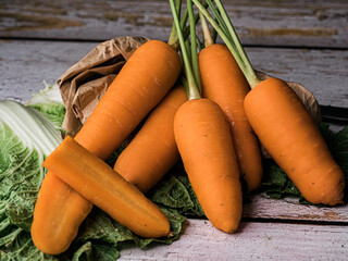 Carrots on a brown textured paper-bag placed on a wooden table against a black backdrop