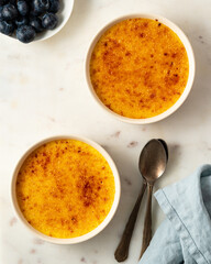 Two ramekin with Creme brulee. Traditional French vanilla cream dessert. Burned cream, burnt or Trinity creme. Spanish crema catalana, rich custard base topped with caramelized sugar, vertical
